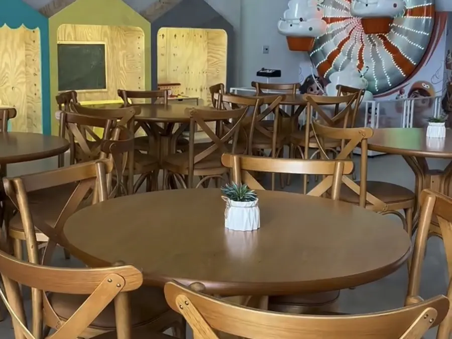 Mesas redondas de madeira para os convidados ao lado da área kids