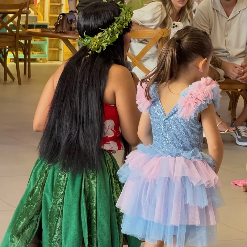 Aniversariante com vestido de tule brincando com personagem durante a festa
