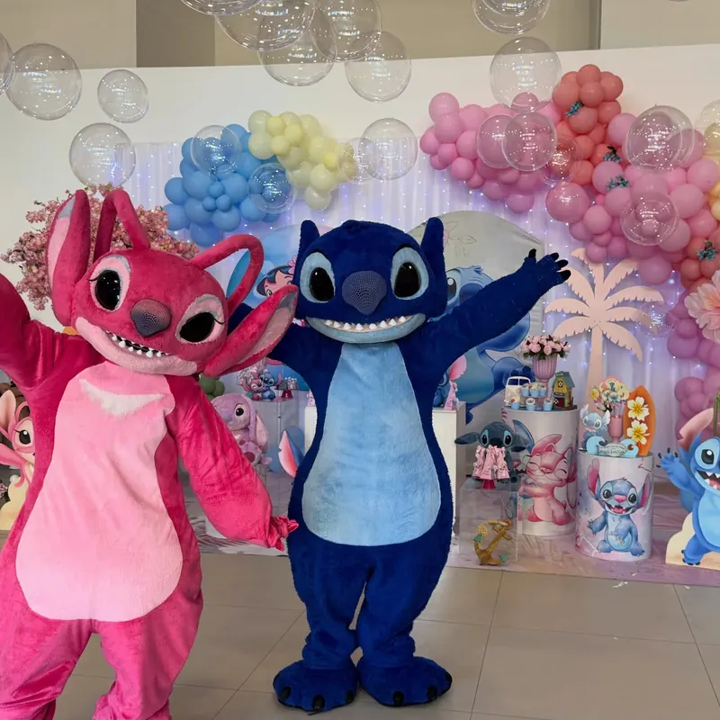 Personagens fantasiados animando a festa infantil em frente ao painel de balões